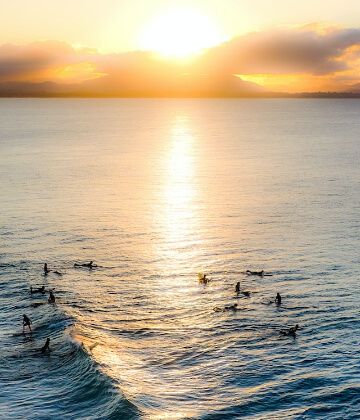 Surfers in the water during the sunset at Byron Bay, Australia