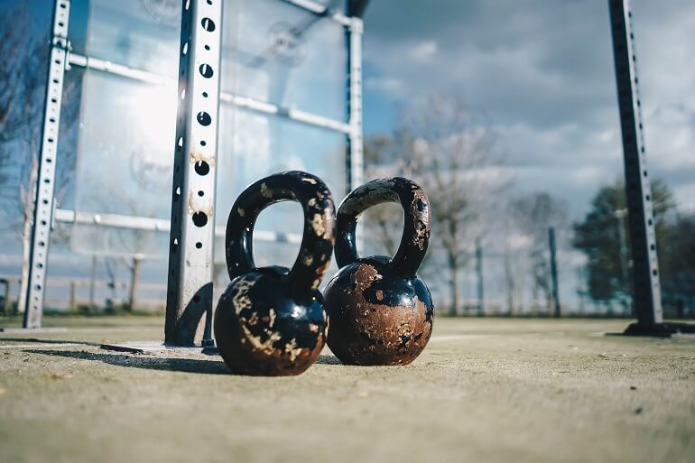 Picture of two kettlebells on the floor outdoors on a suny day