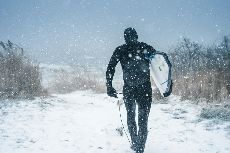 Guy going to surf on a snowy day