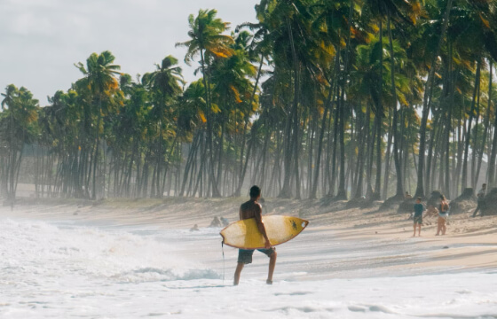 Surfer walking out of the water at Cabo de Santo Agostinho, Brazil