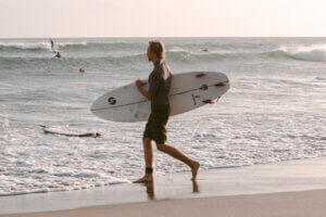 Surfer entering the water with some surfers in the background