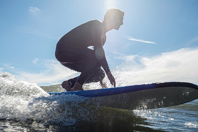 Surfer on a begginer board practicing the stand-up technique