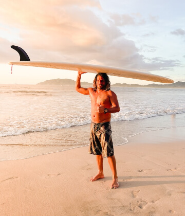 Surfer with a long board over his head at Tamarindo, Costa Rica