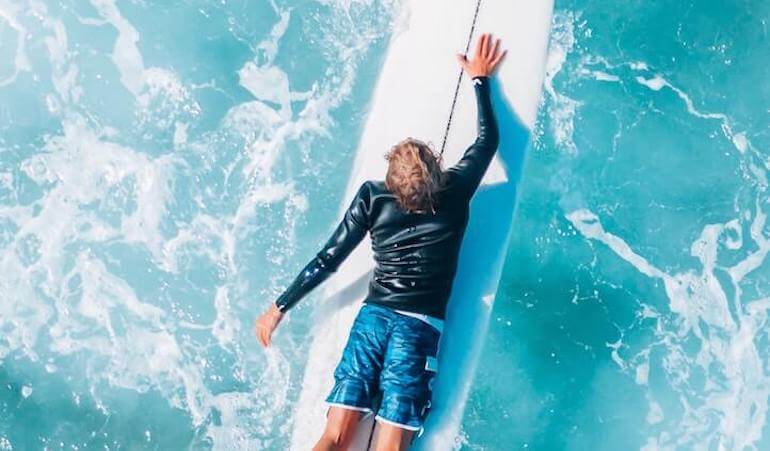 Surfer paddling on his board 