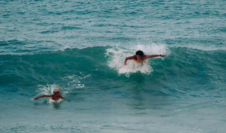 Two surfers paddling for a wave 