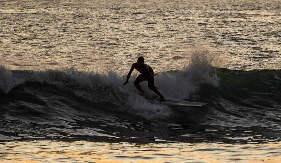 man surfing in the waves during evening