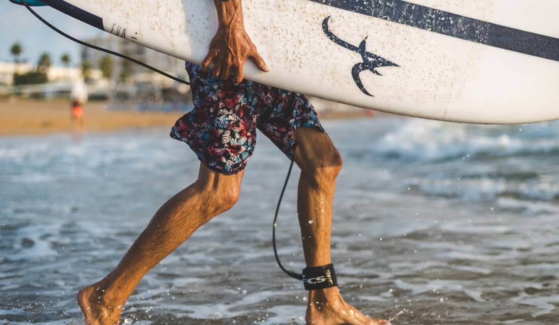 man walking with surfboard