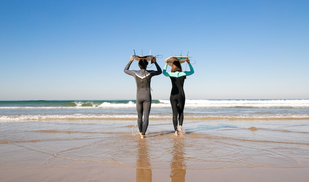 Couple carrying surfboards to water