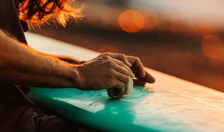 Guy waxing his board 