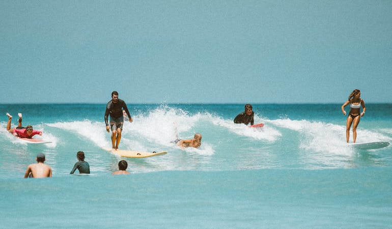 A bunch of surfers catching a wave 